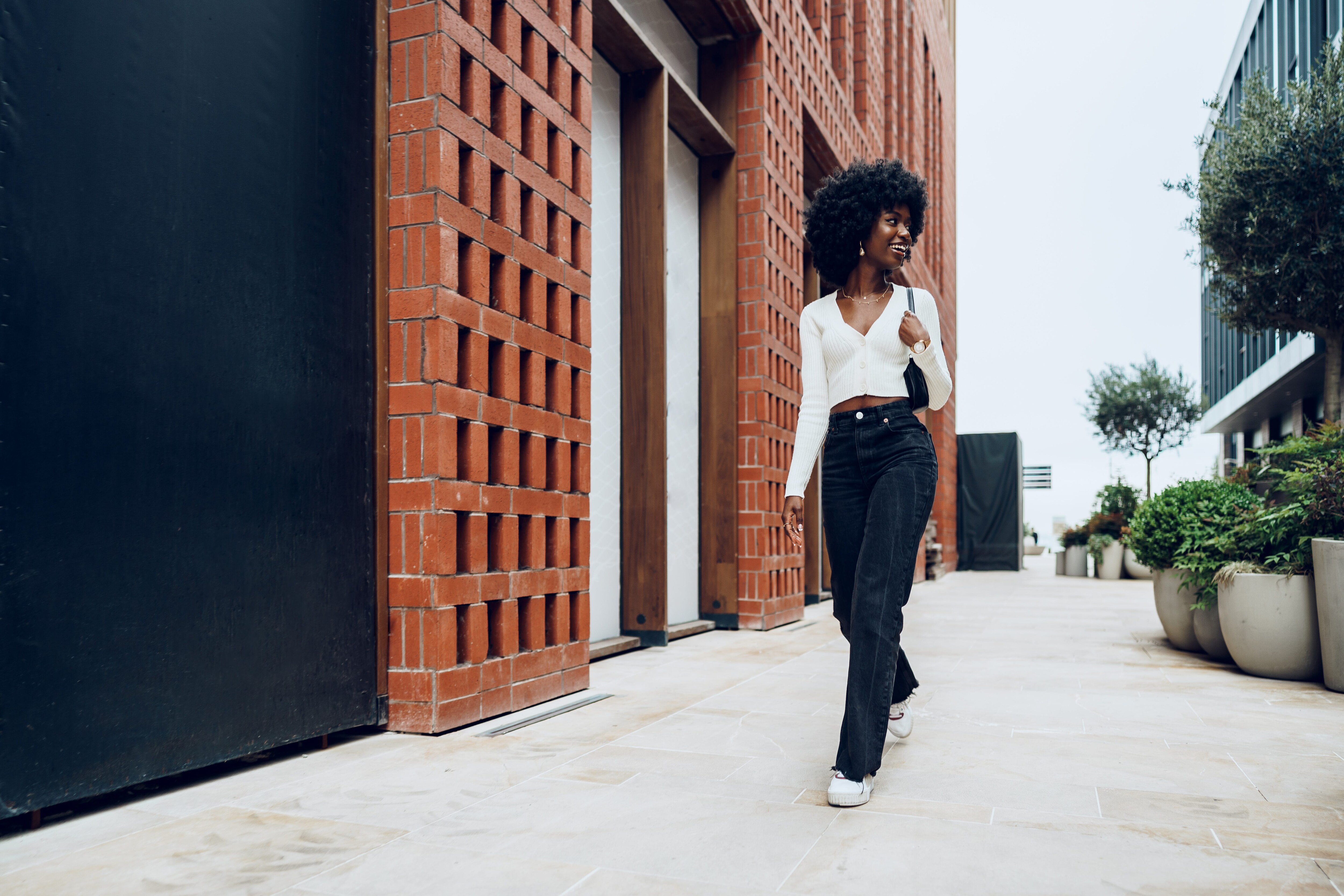 Black woman walking while wearing sneakers as flat shoes.jpeg
