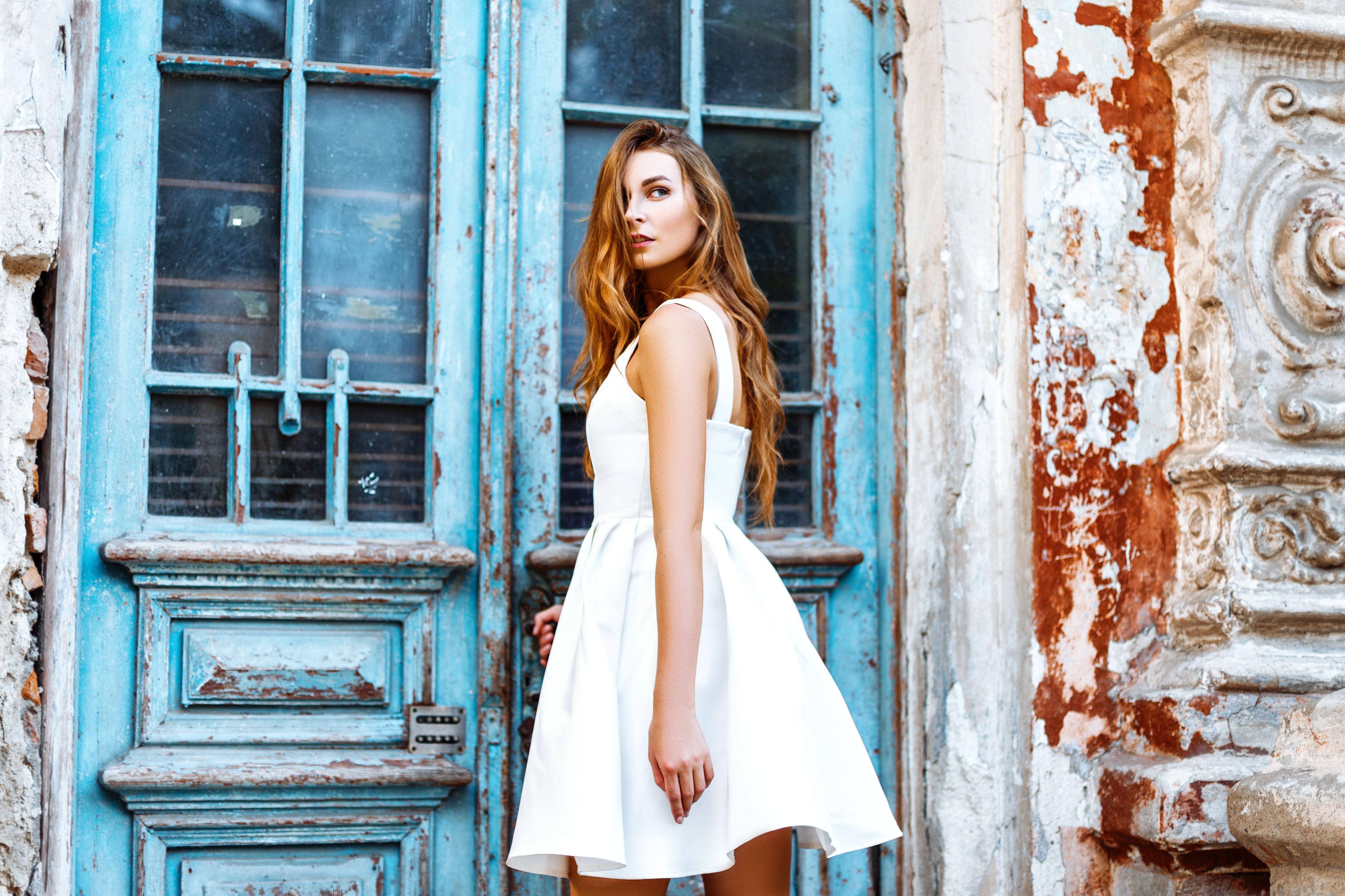 Woman in a white sleeveless A line dress looking over her shoulder.jpeg