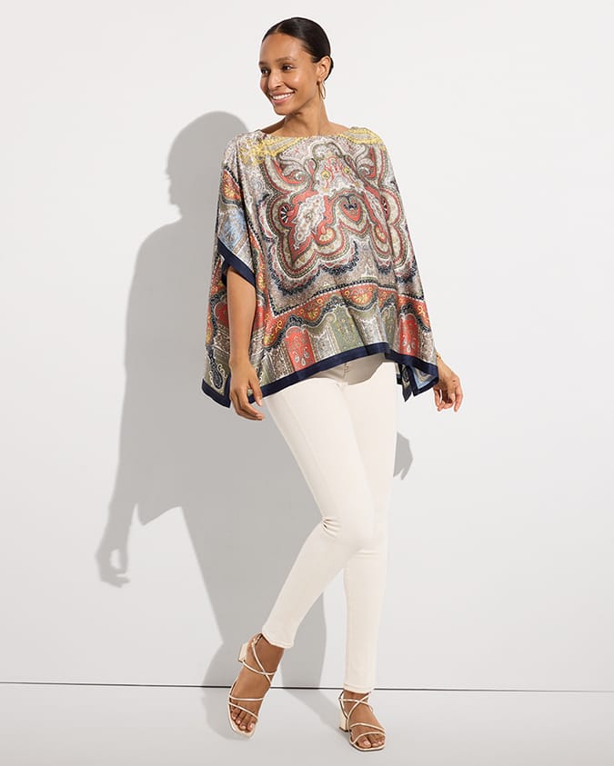 Woman wearing colorful poncho and white jeans