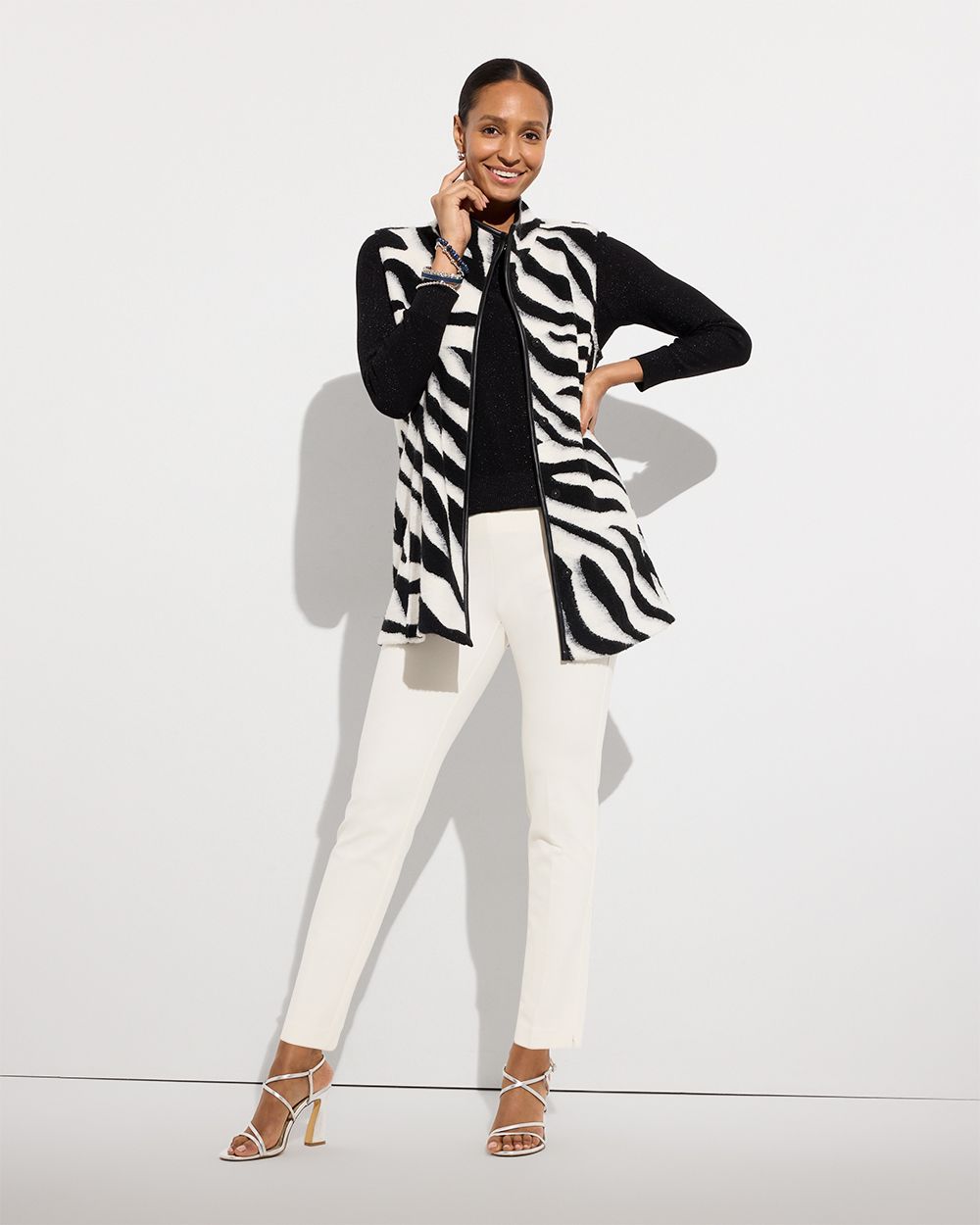 Woman wearing black long sleeve shirt with zebra print vest and white pants