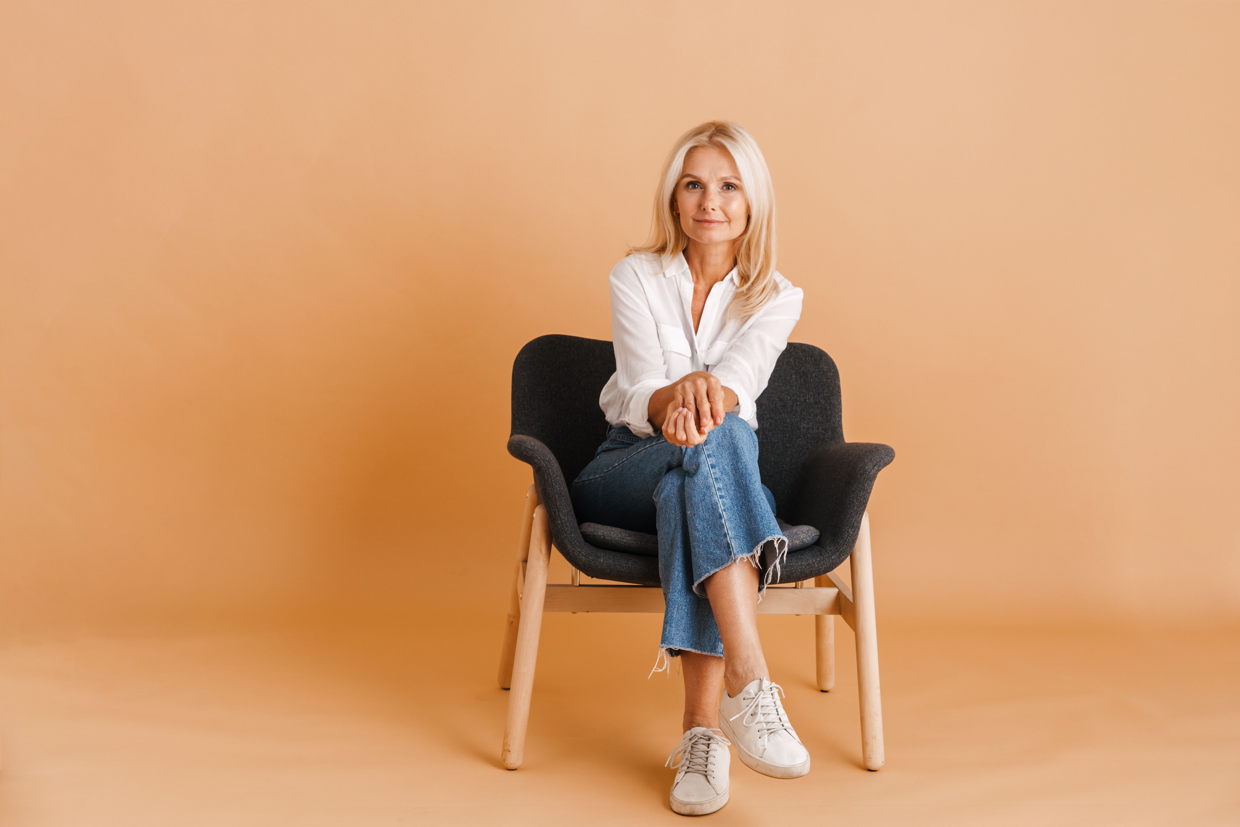 Blonde woman sitting in a chair wearing a white shirt and cropped wide-leg jeans.jpeg