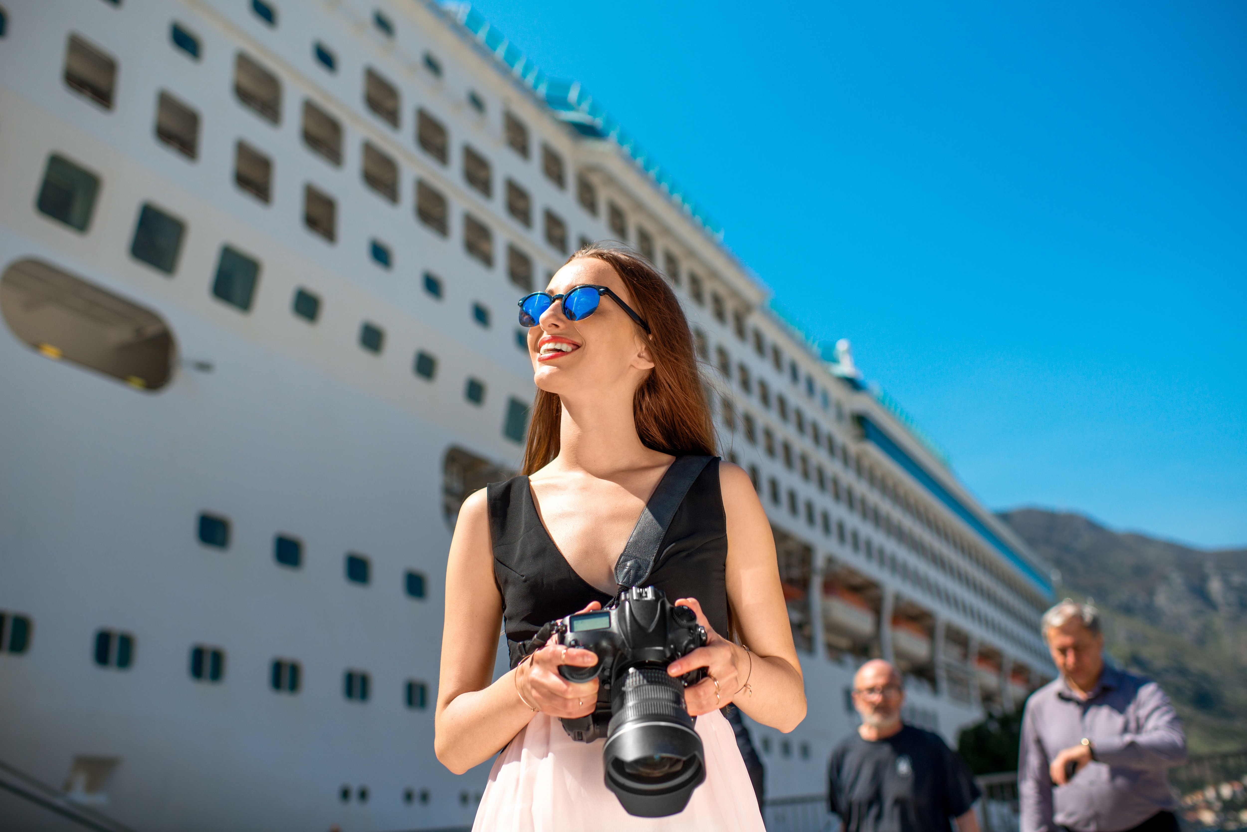 Woman holding a camera in front of a large cruise ship.jpeg