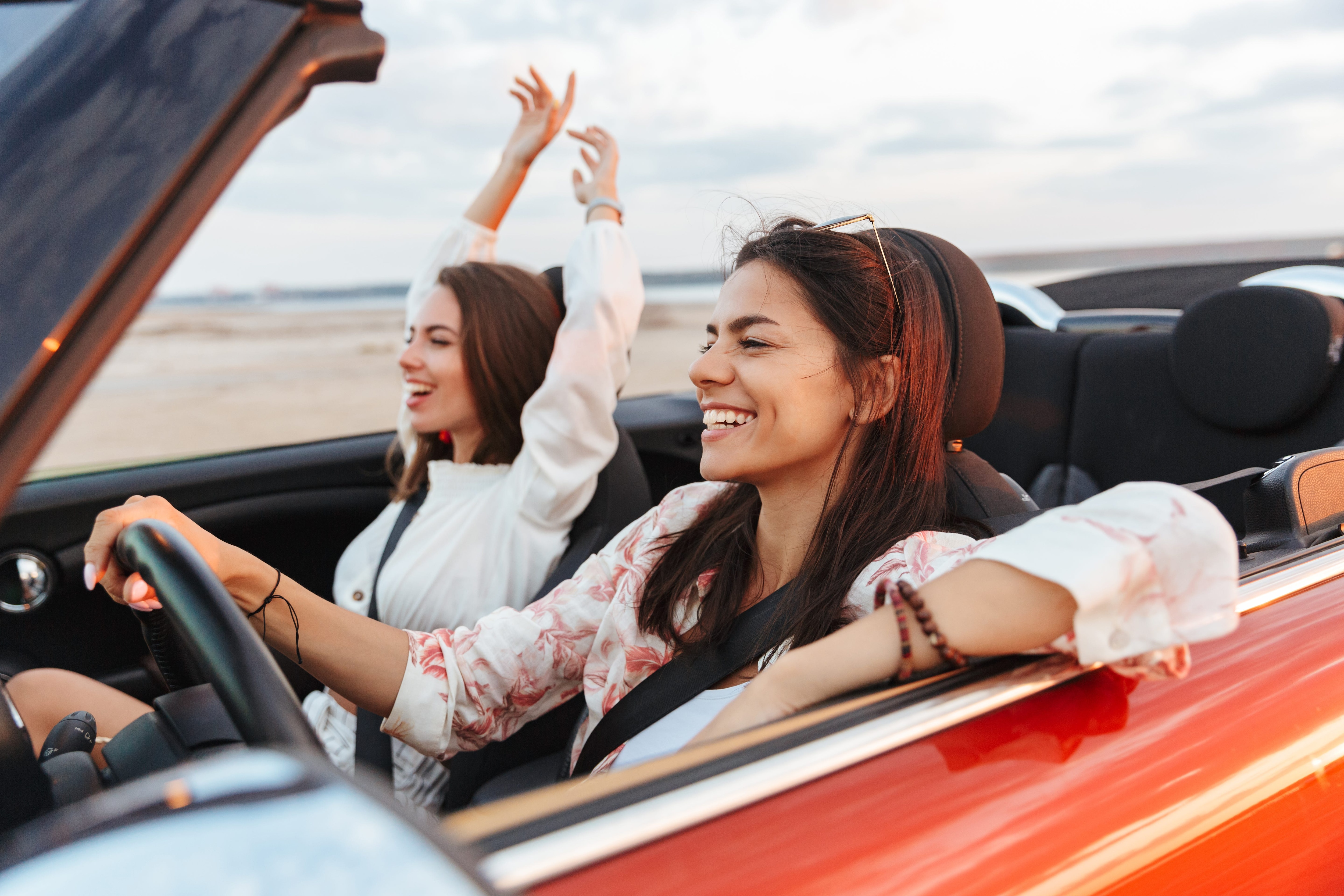 Two happy women in a convertible enjoying a road trip.jpeg