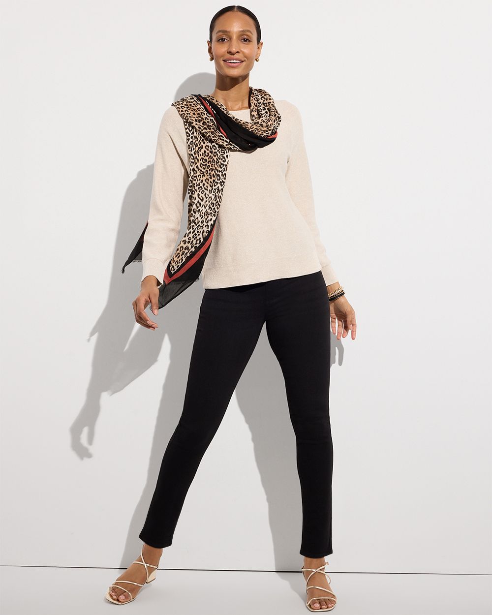 Woman wearing cream sweater with scarf and black slim pants