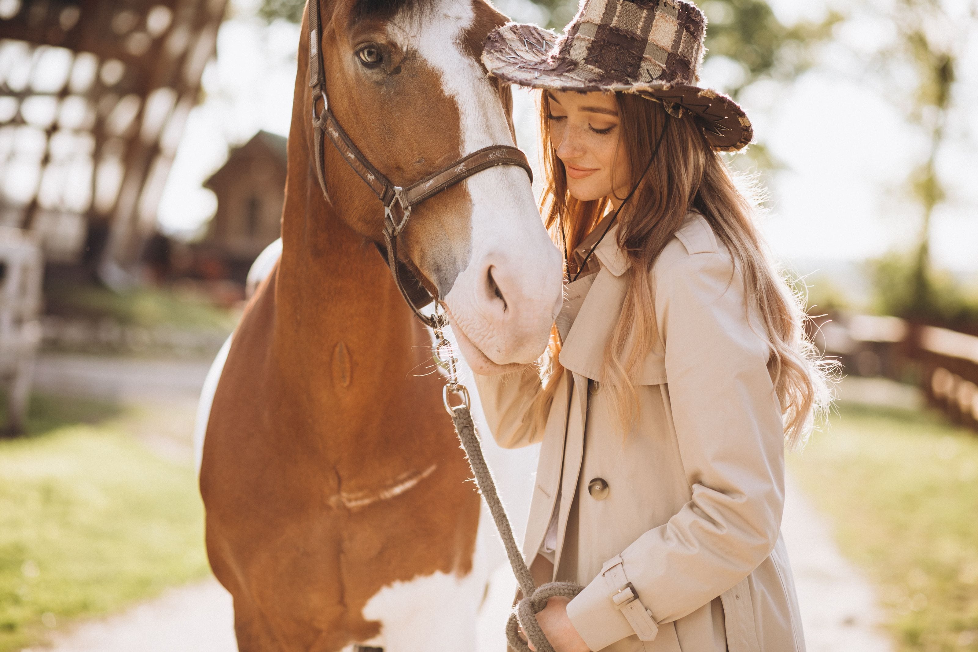Woman wearing a trench coat and cowboy hat standing beside a horse.jpeg